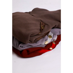 Stack of folded bluza lara garments with mikropolarem alpejskim in earthy tones featuring gold button accents