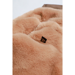 A plush peach faux fur blanket with soft texture and black tag paired with kurtka przeciwdeszczowa pikowana for dogs