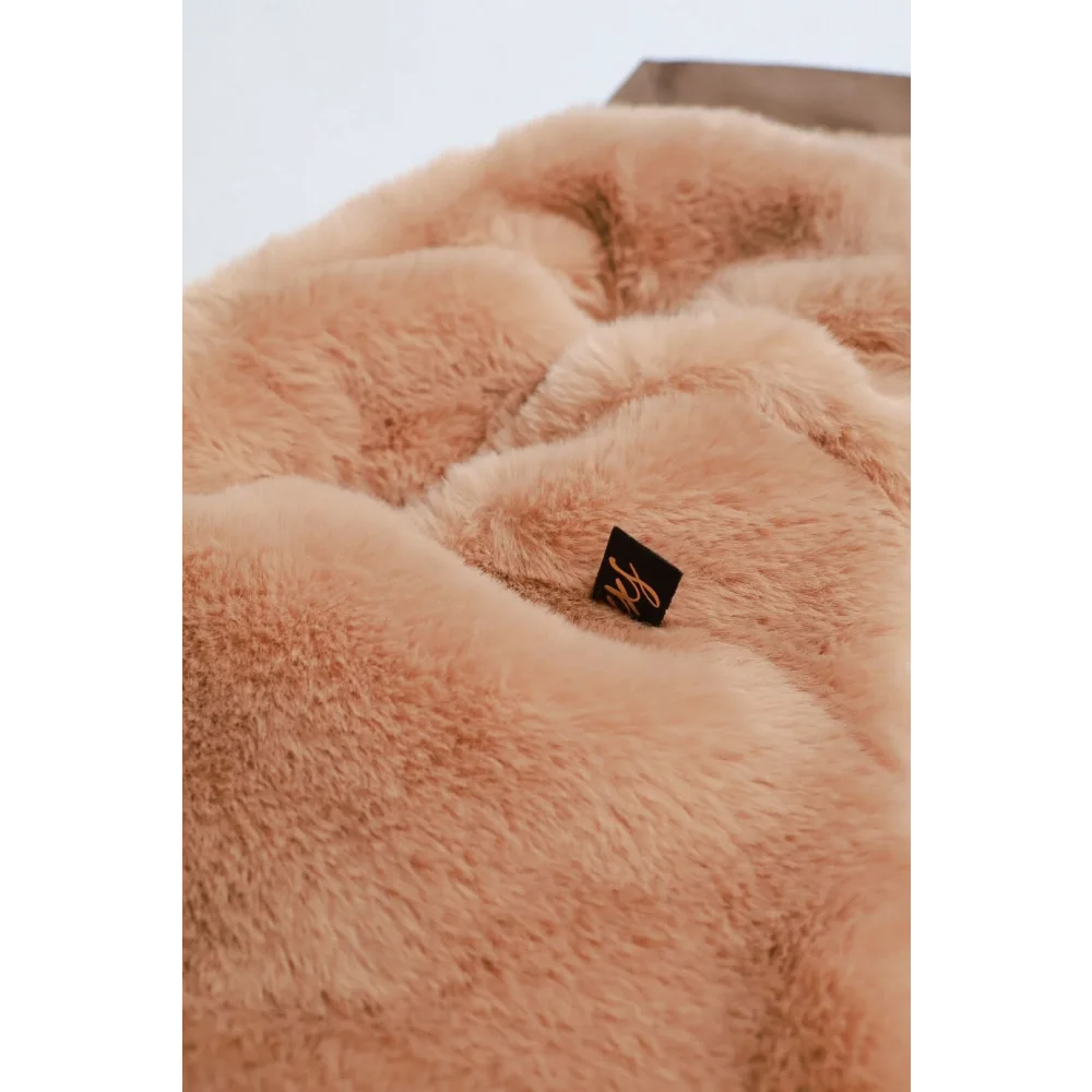 A plush peach faux fur blanket with soft texture and black tag paired with kurtka przeciwdeszczowa pikowana for dogs
